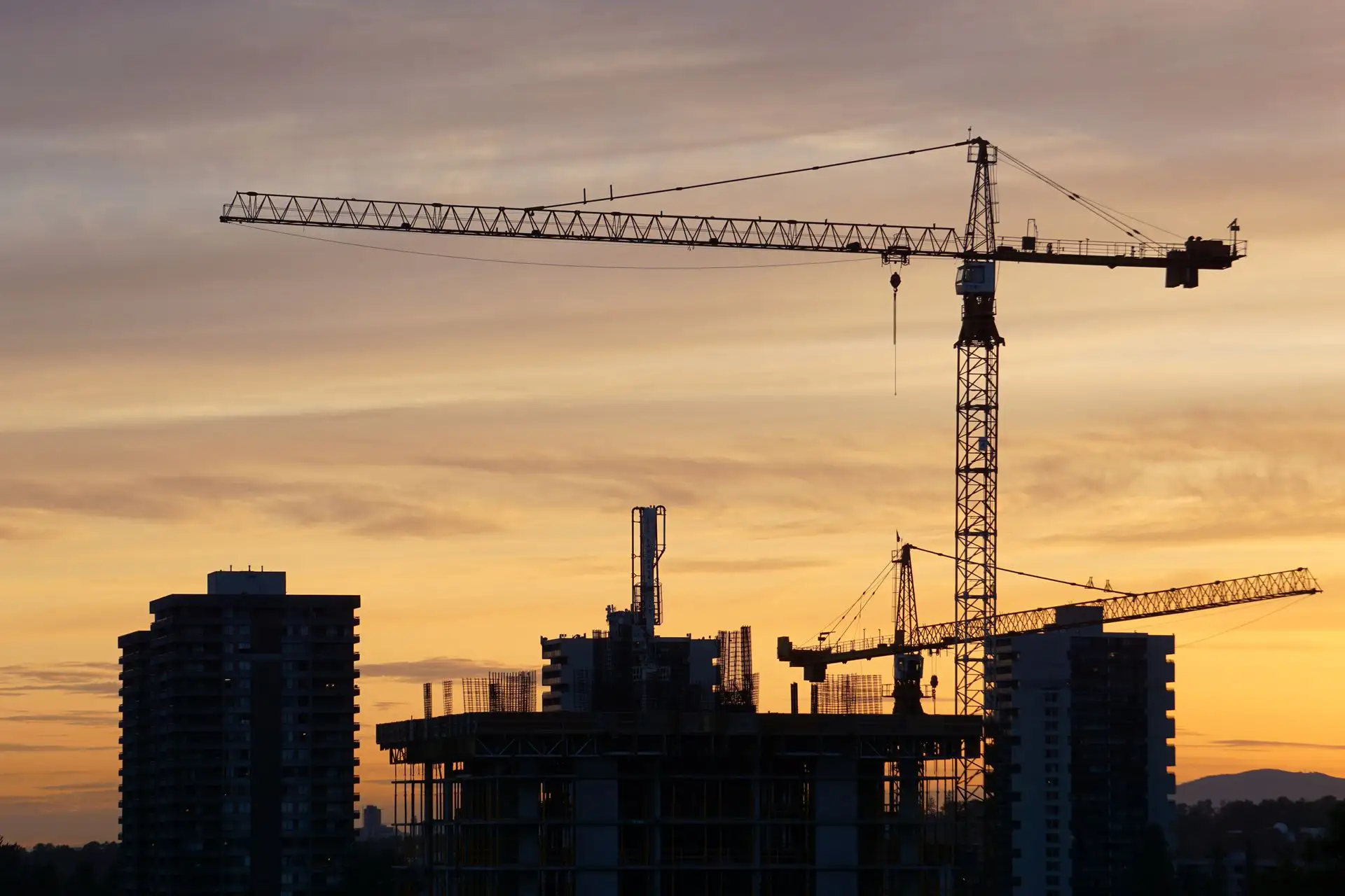 Tower crane over a residential building under construction at dusk